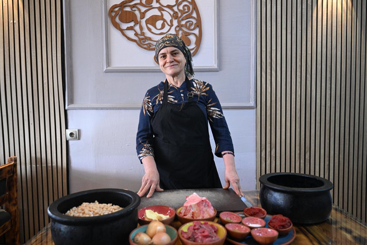 Chef Cennet Celik explains how white beans are slow-cooked in clay pots, a ritual that blends local flavors with the communal traditions of Nevsehir, Türkiye, March 1, 2026. (AA Photo)