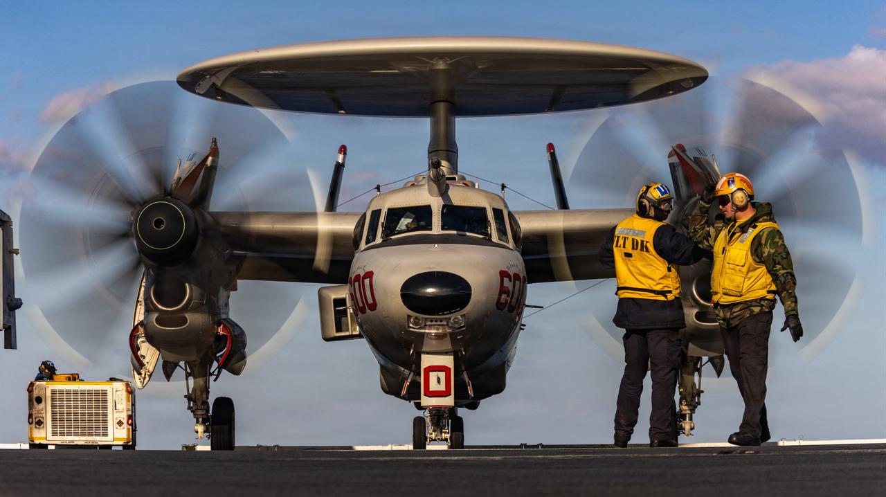 US Navy sailors signaling to an E-2D Hawkeye aircraft as it taxis on the flight deck of USS Gerald R. Ford (CVN 78), on February 28, 2026. (Photo by Sergeant First Class Michael Hunnisett/US CENTCOM/AFP)
