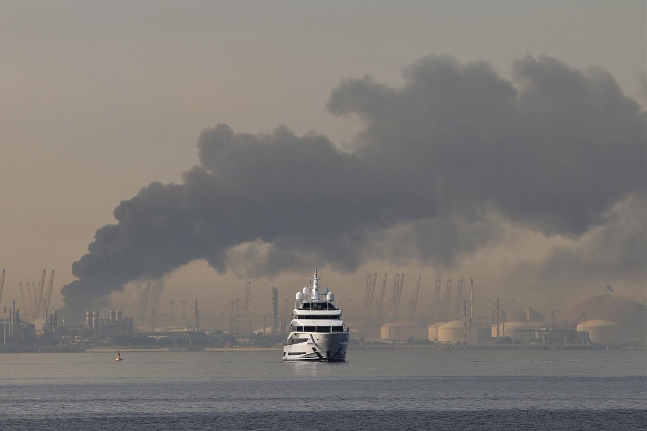 A yacht sails past a plume of smoke rising from the port of Jebel Ali following a reported Iranian strike in Dubai on March 1, 2026. (AFP Photo)