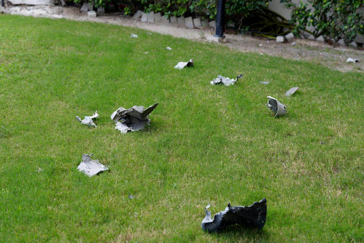 Shrapnel is scattered on the lawn outside the damaged Crown Plaza hotel, following an Iranian military strike, in Manama on March 1, 2026.  (AFP Photo)