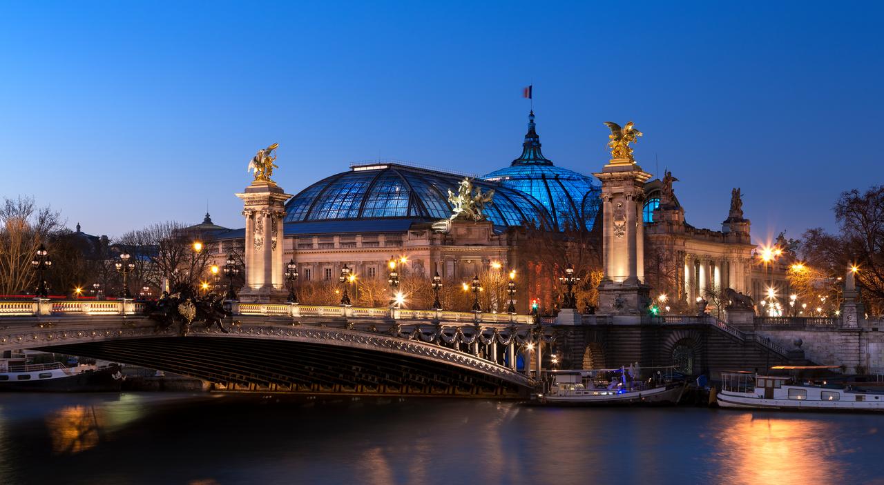 The Grand Palais and the Alexandre III Bridge illuminate the Seine in Paris during the evening, France, accessed on March 10, 2026. (Adobe Stock Photo)
