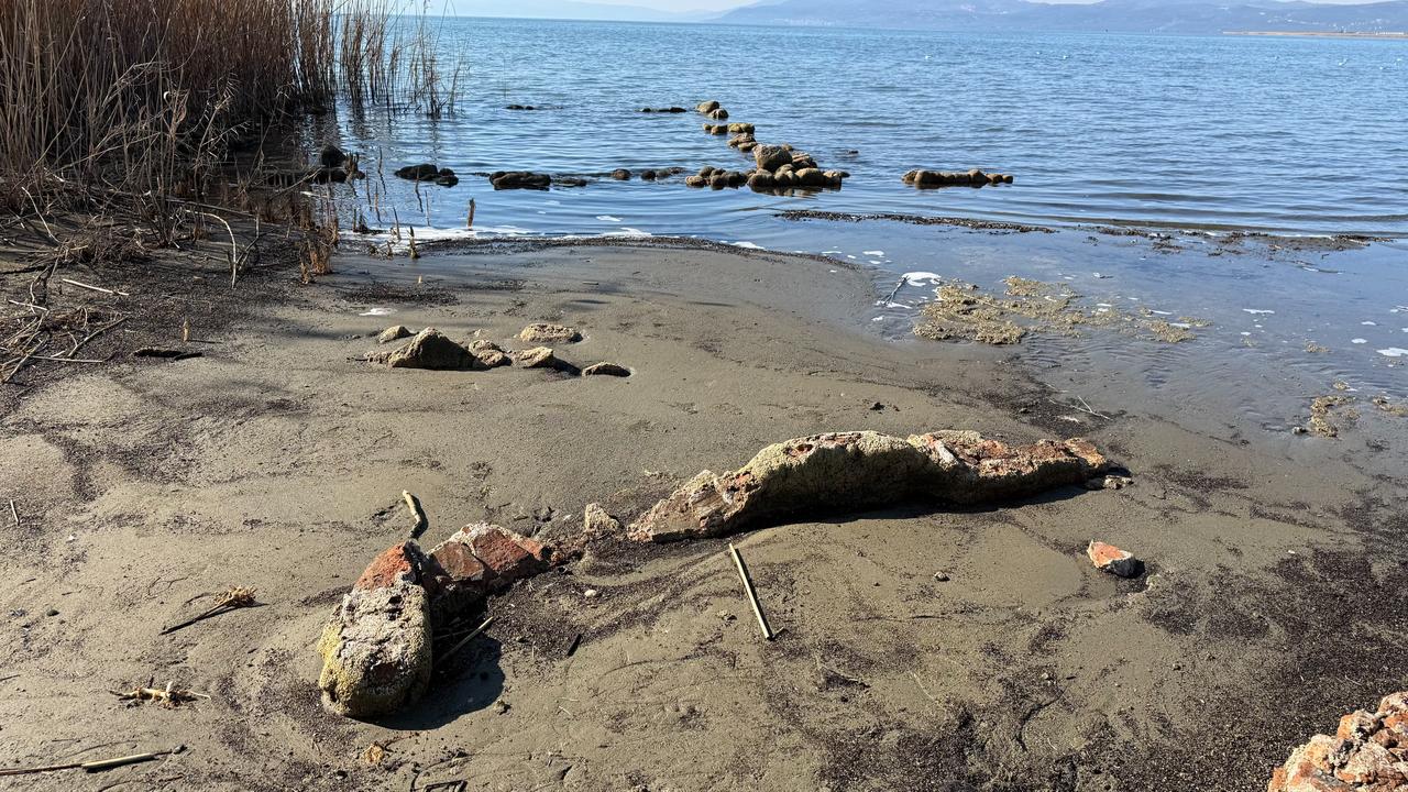 Structural remains partially buried in sand become visible along the retreating shoreline of Lake Iznik, where experts suspect the presence of another historic religious building in Bursa, Türkiye, March 7, 2026. (IHA Photo)