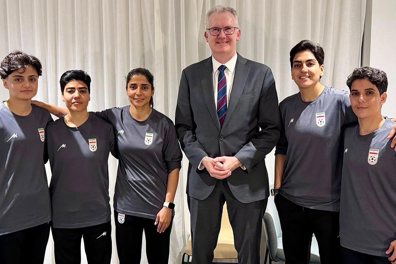 Australia's Home Affairs minister, Tony Burke, is posing with the five Iranian women football players who applied for asylum after competing in the Women's Asia Cup tournament being played in Australia. (AFP Photo)