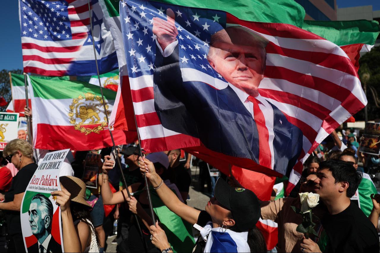 People hold signs in support of Reza Pahlavi, son of the last shah of Iran, along with a flag of US President Donald Trump in Los Angeles, California on March 7, 2026. (AFP Photo)