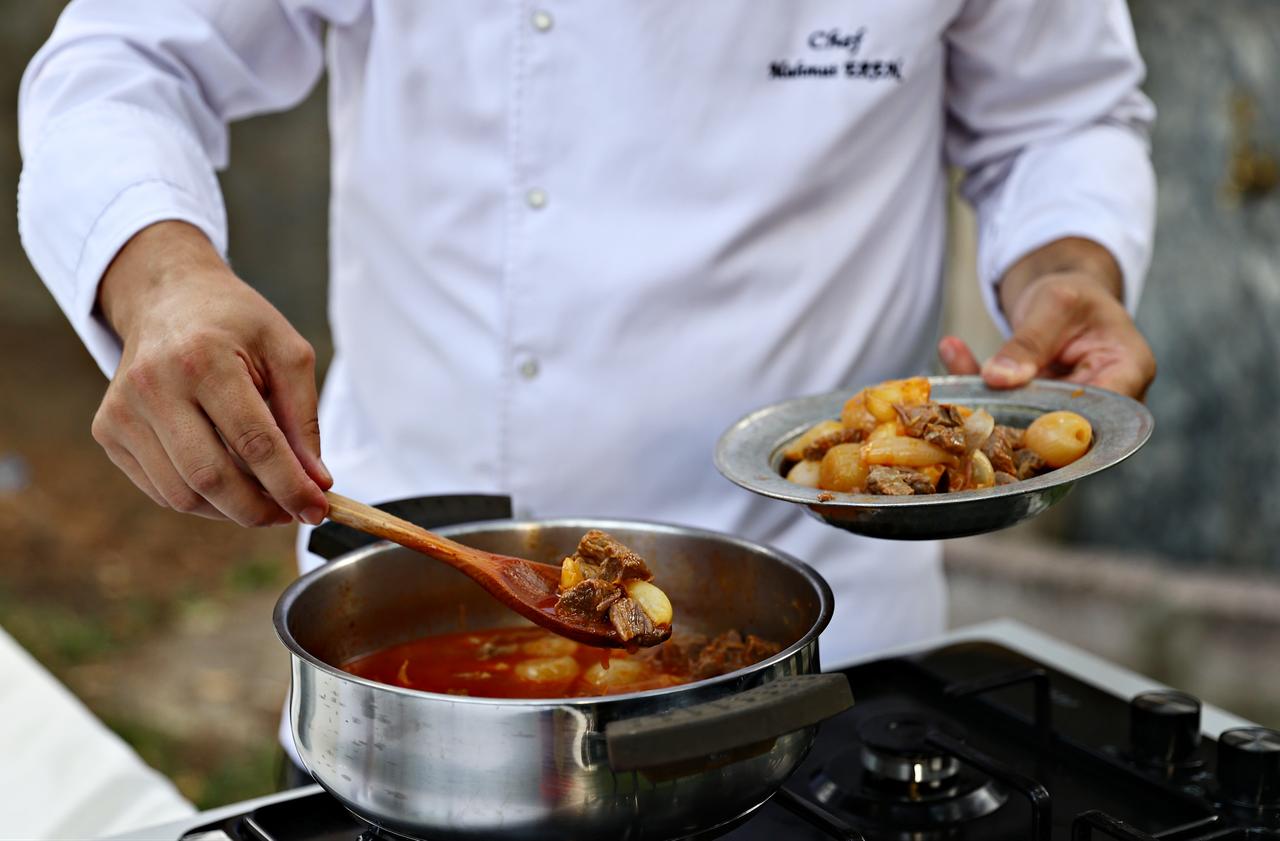 A chef serves a portion of sarimsakli et, a traditional meat dish cooked with whole garlic cloves, during its preparation as part of a regional cuisine presentation in Türkiye, March 12, 2026. (AA Photo)