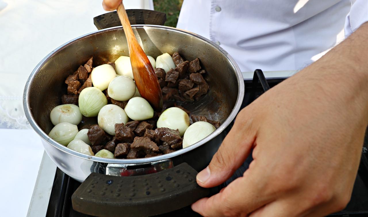 A chef cooks pieces of meat and whole onions while preparing sarimsakli et, a traditional garlic-based dish known in regional Turkish cuisine, in Türkiye, March 12, 2026. (AA Photo)