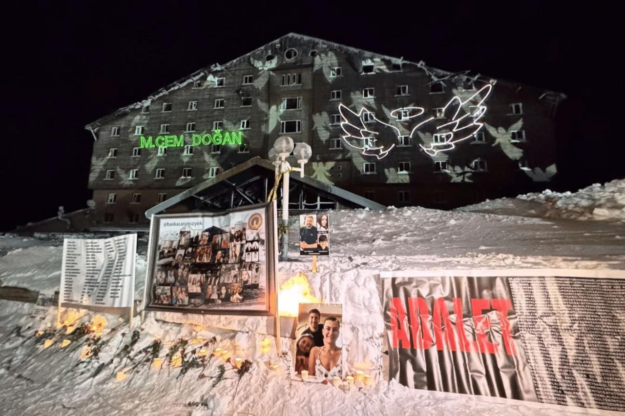 Families light candles and place flowers outside the Grand Kartal Hotel during the Kartalkaya fire anniversary memorial, Bolu, Türkiye, January 21, 2026. (AA Photo)