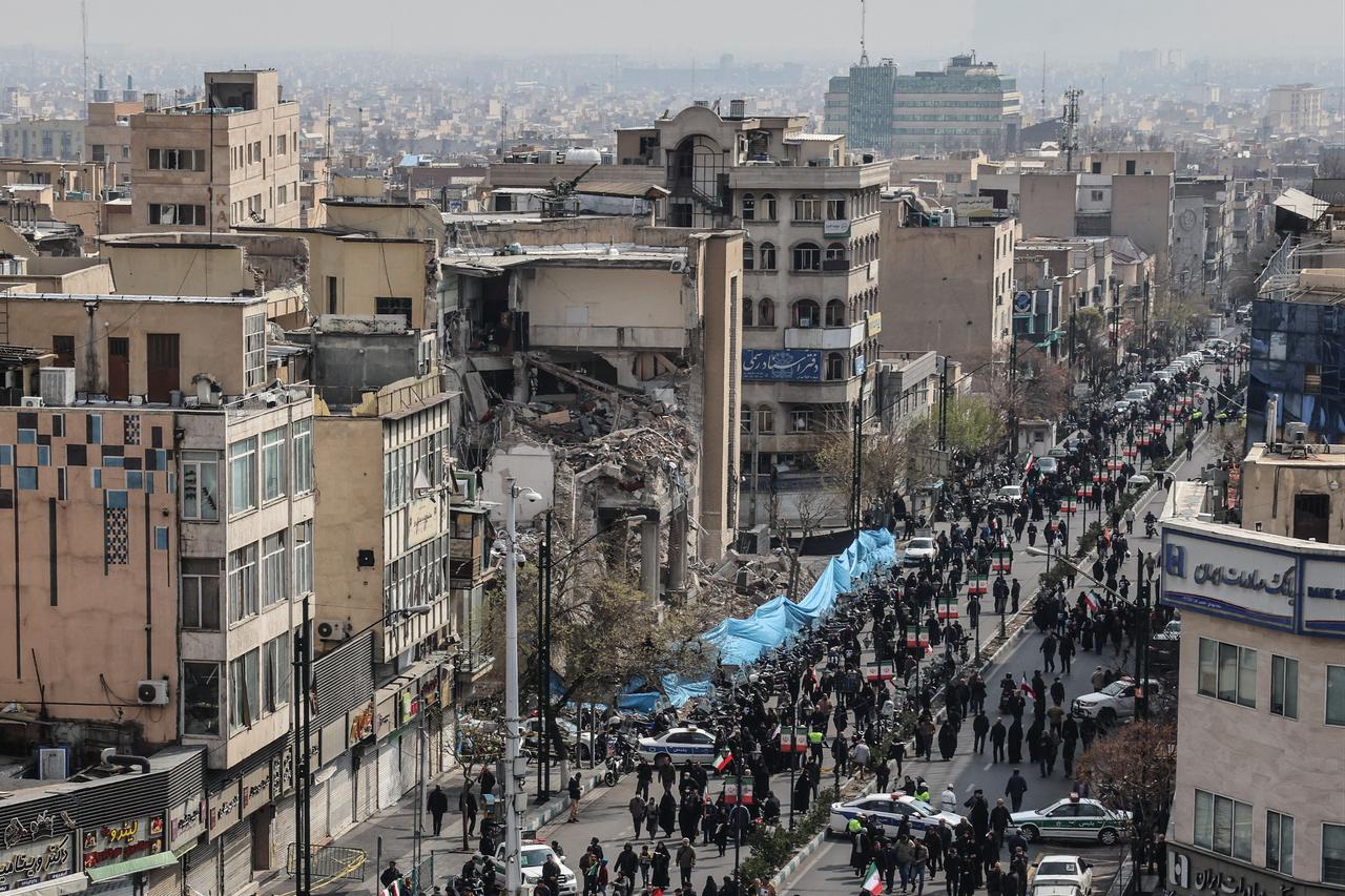 Iranians walk past a damaged building as they attend the funerals of Iran's Revolutionary Guards Corps (IRGC) commanders, in Tehran on March 11, 2026. (AFP Photo)