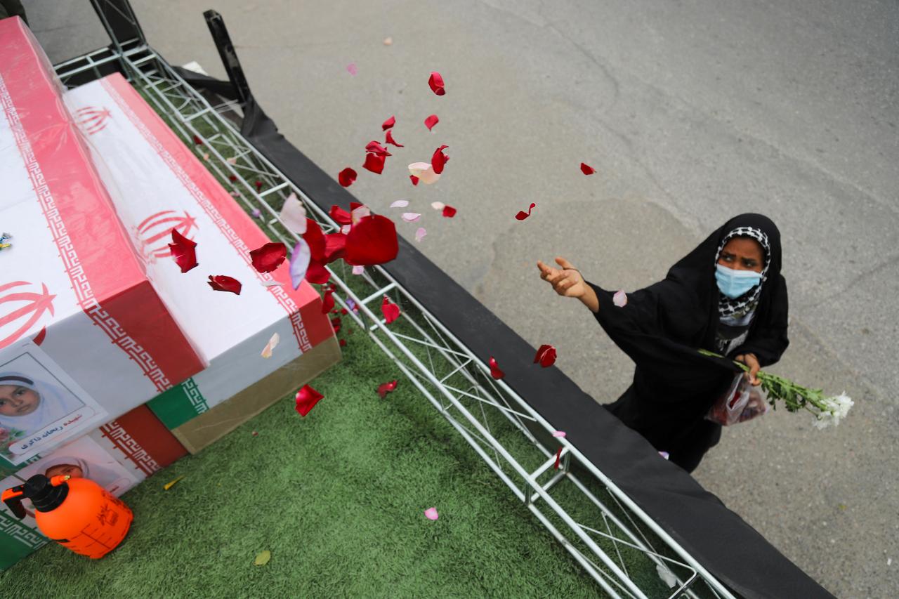 In this picture obtained from Iran's ISNA news agency, a mourner sprays flower petals on the coffins of children who were killed in a reported strike on a primary school in Iran’s Hormozgan province during a funeral in Minab on March 3, 2026. (AFP Photo)