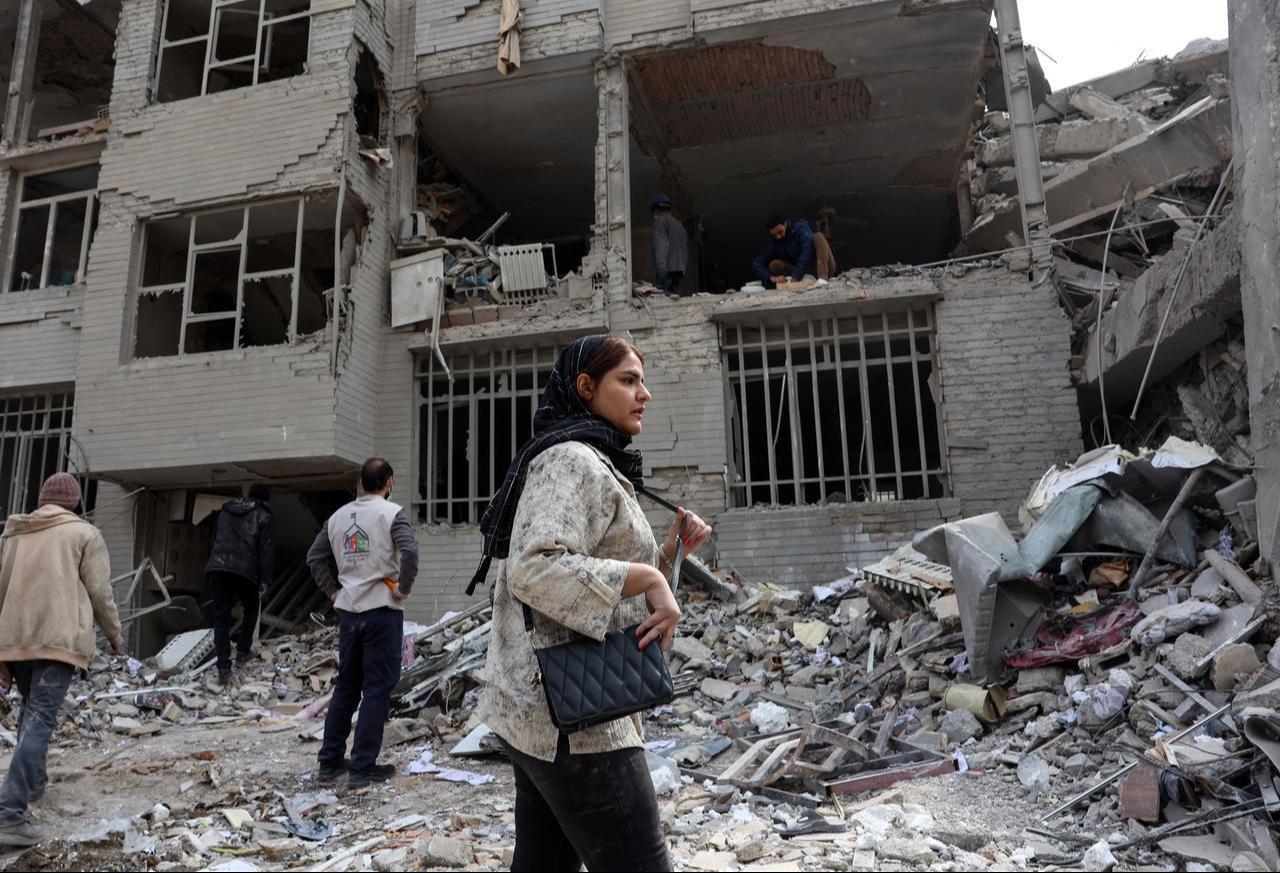 A woman stands in front of a destroyed residential building as residents collect their belongings from the rubble in Tehran on March 12, 2026. (AFP Photo)