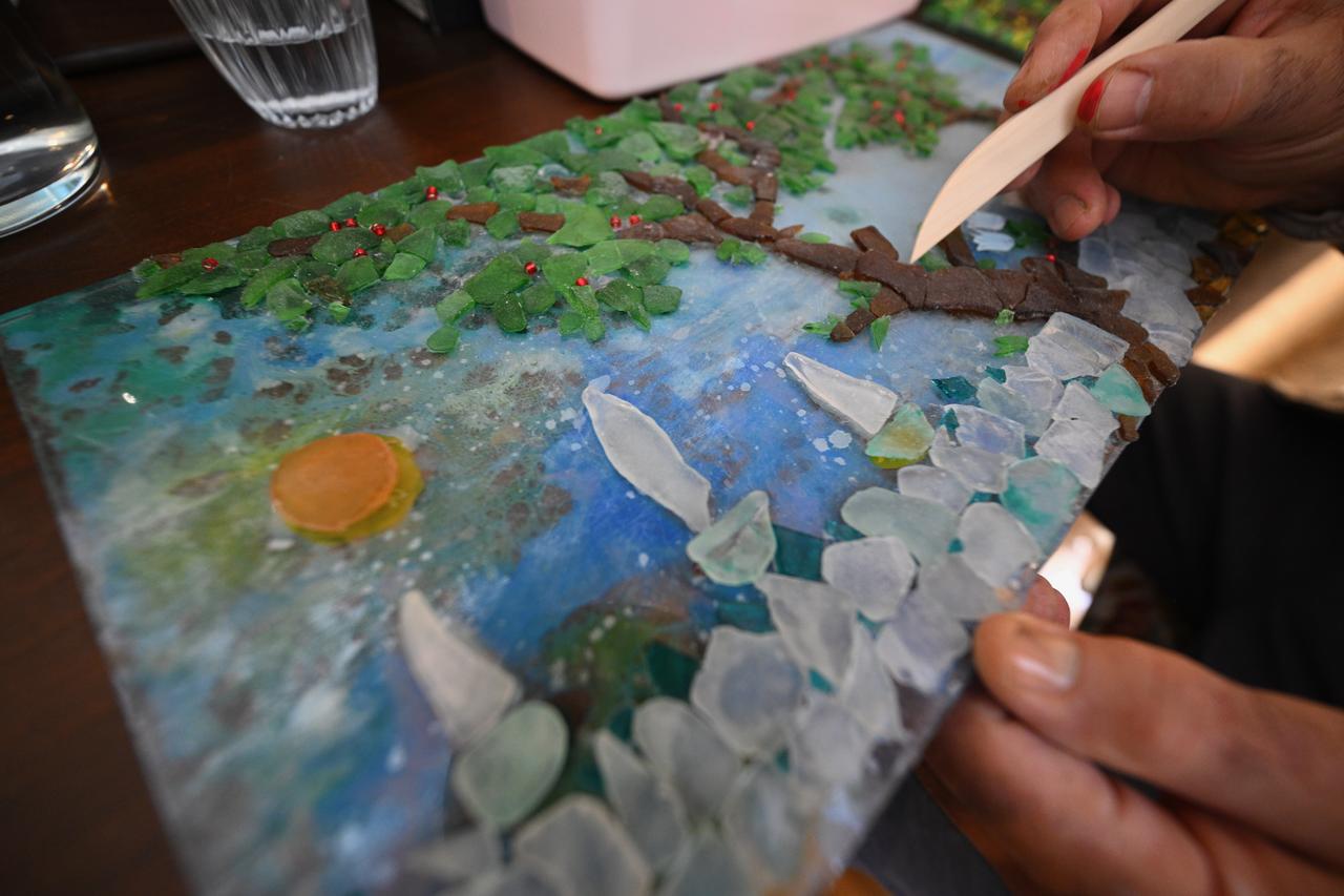 Prof. Dr. Murat Kaya arranges decorative materials while working on a mixed-media artwork made with glass and natural elements in Duzce, Türkiye, March 15, 2026. (AA Photo)