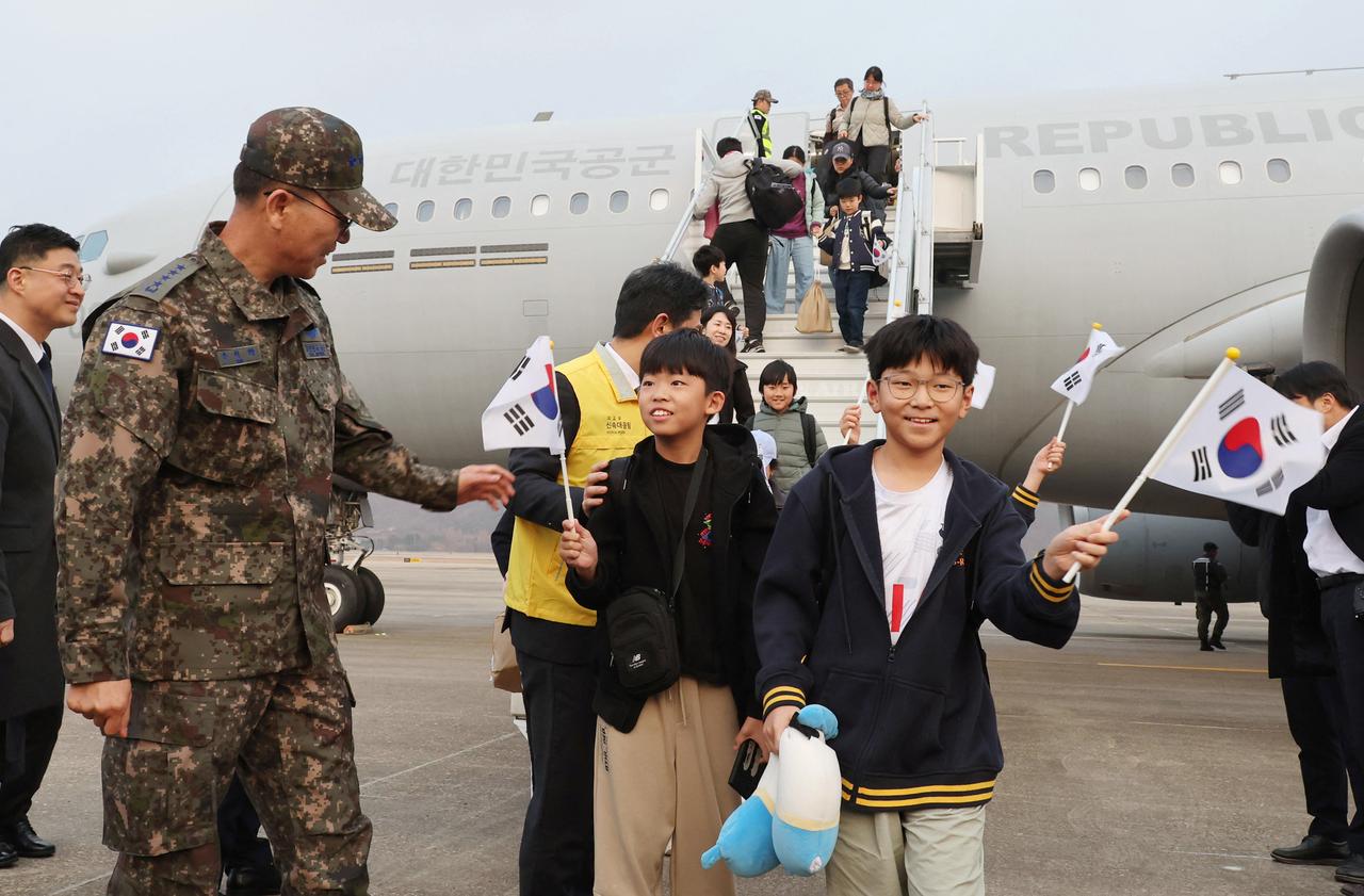 South Korean nationals returning from Saudi Arabia wave the national flags after disembarking from a South Korean Air Force KC-330 transport aircraft at Seoul Air Base in Seongnam, March 15, 2026. (AFP Photo)
