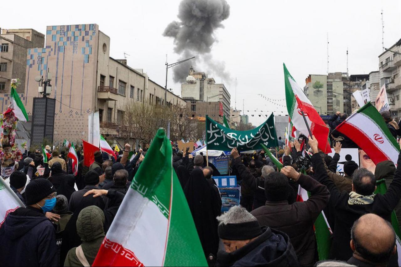 Smoke rises after an explosion during the World Quds Day march as participants carry Iranian flags and banners in Tehran, Iran, on March 13, 2026. (Iranian President's Press Office/Handout)