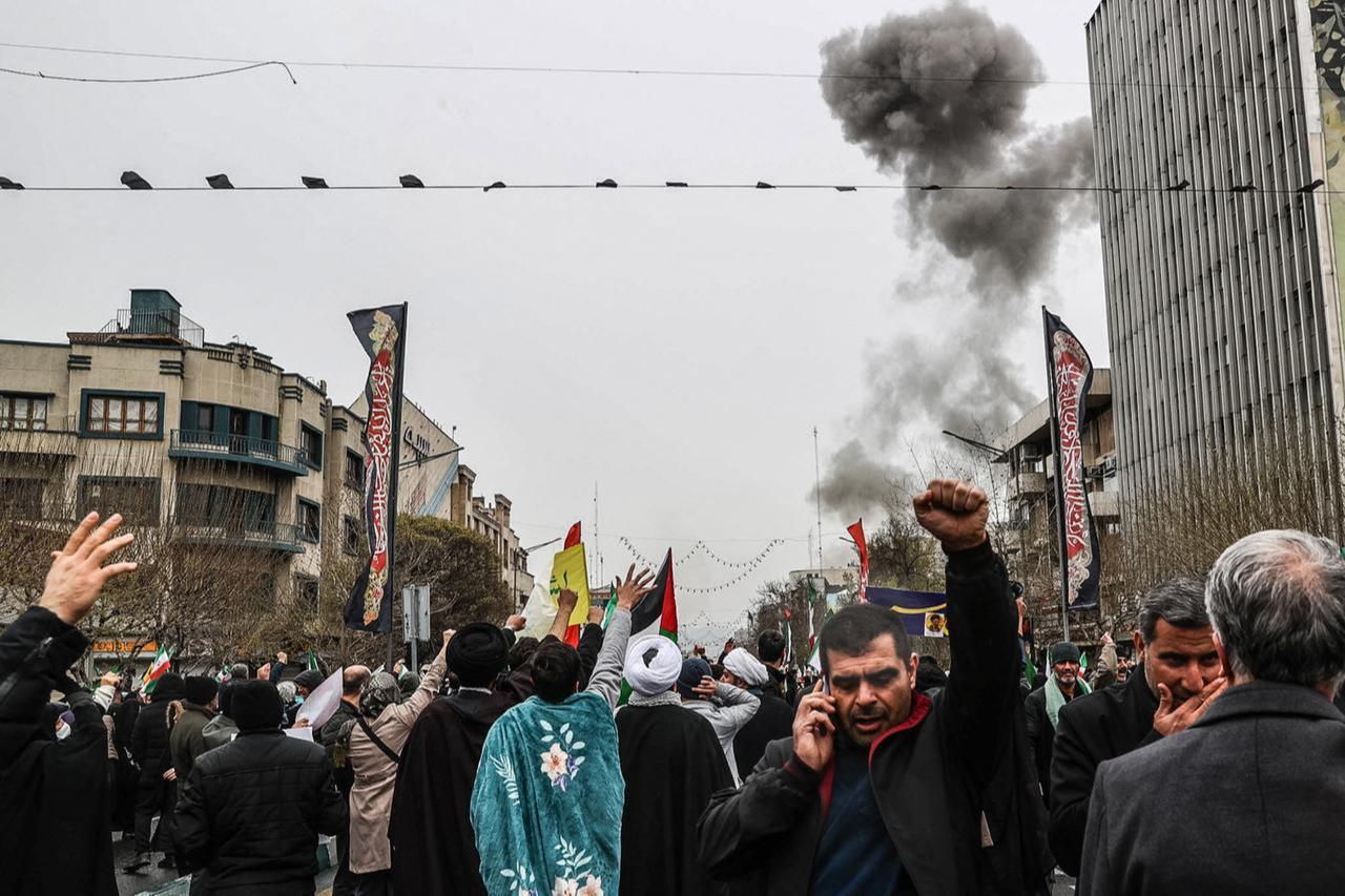 Black smoke rises following an airstrike as Iranians take part in the Al-Quds (Jerusalem) Day rally in Tehran on March 13, 2026. (AFP Photo)