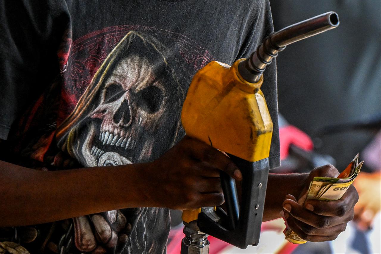 An employee collects cash after filling petrol in a motorbike at a filling station in Wellawatte on the outskirts of Colombo on March 16, 2026. (AFP Photo)