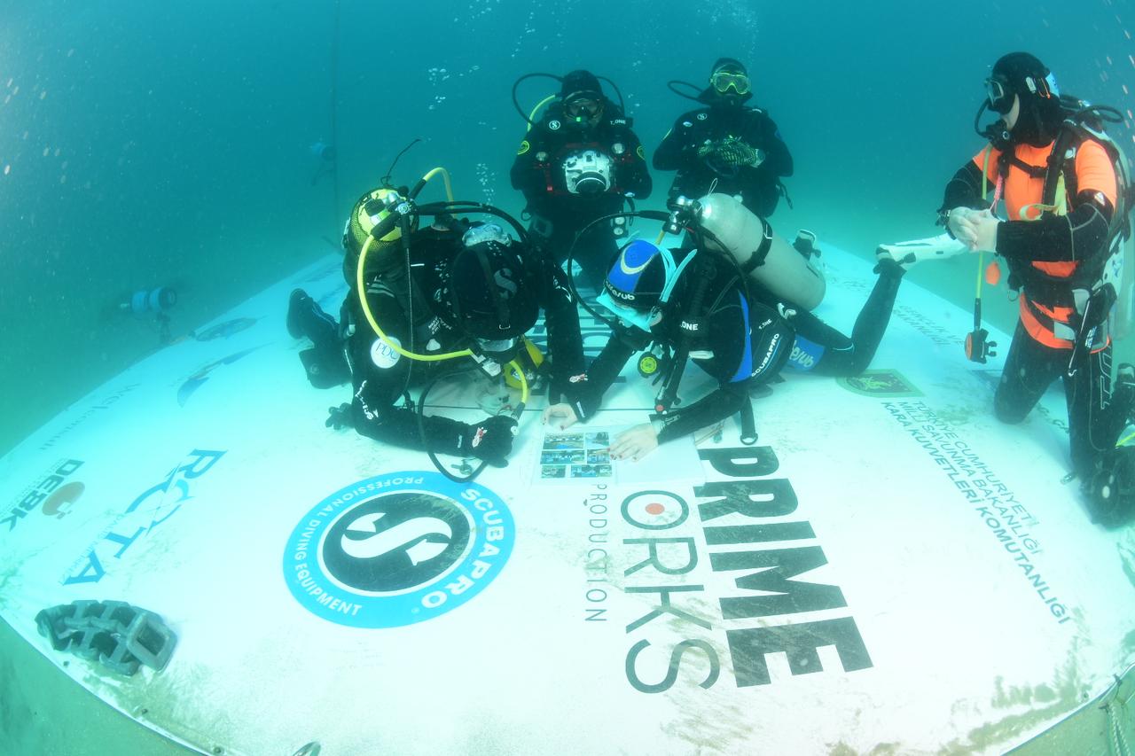 Support divers monitor professional diver Mazlum Kibar (L) as he writes notes on a board during his attempt to set a Guinness World Record for the longest scuba dive in cold water at Anzac Cove on the Gallipoli Peninsula in Canakkale, Türkiye, March 15, 2026. (AA Photo)
