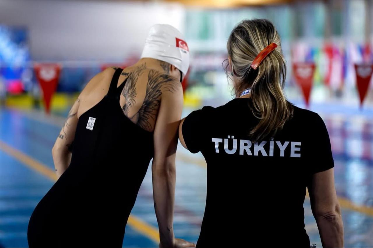 Turkish para swimmer Defne Kurt prepares to compete while receiving last-minute guidance from a coach beside the pool during an international competition on March 15, 2026. (Photo via Instagram/@dafnekurt)