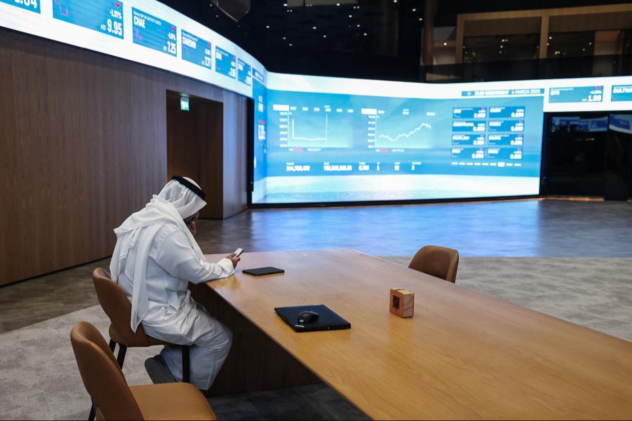 A man sits by a screen displaying stock indices at the Dubai Financial Market (DFM) stock exchange in Dubai, March 4, 2026. (AFP Photo)