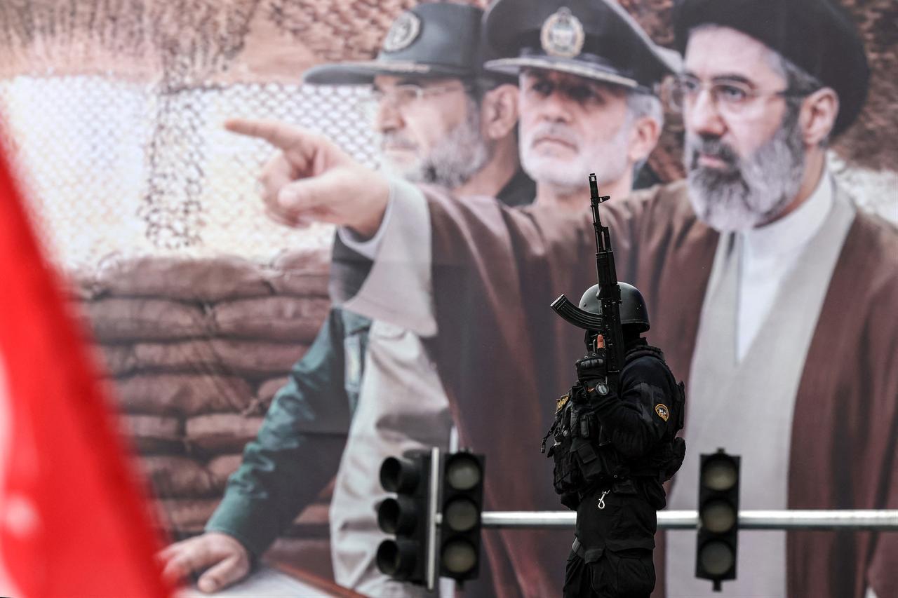An Iranian security force officer stands guard next to a huge billboard of Iran's newly nominated supreme leader, Mojataba Khamenei, during the Al-Quds Day rally in Tehran, March 13, 2026. (AFP Photo)