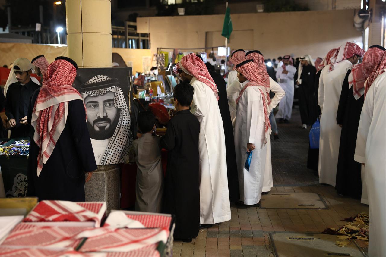A portrait of Saudi Arabia’s de facto ruler Mohammed bin Salman stands beside a stall where Saudis pause in the oldest popular Al-Zel market in downtown Riyadh on March 12, 2026. (AFP Photo)