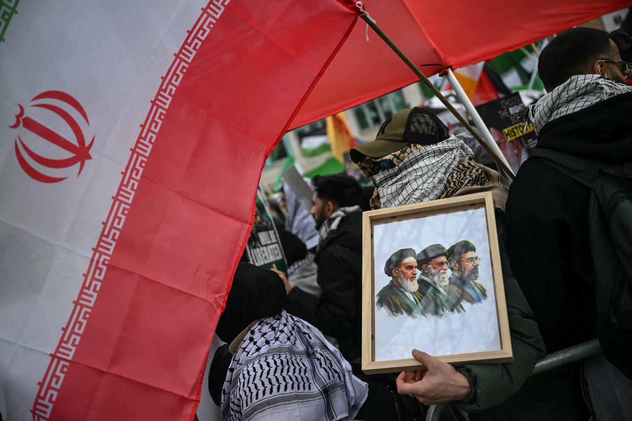 A protester holds a framed image of (L to R) Iran's late supreme leader Ruhollah Khomeini, late Ali Khamenei, and new Supreme Leader Mojtada Khamenei during an annual protest in central London, March 15, 2026. (AFP Photo)