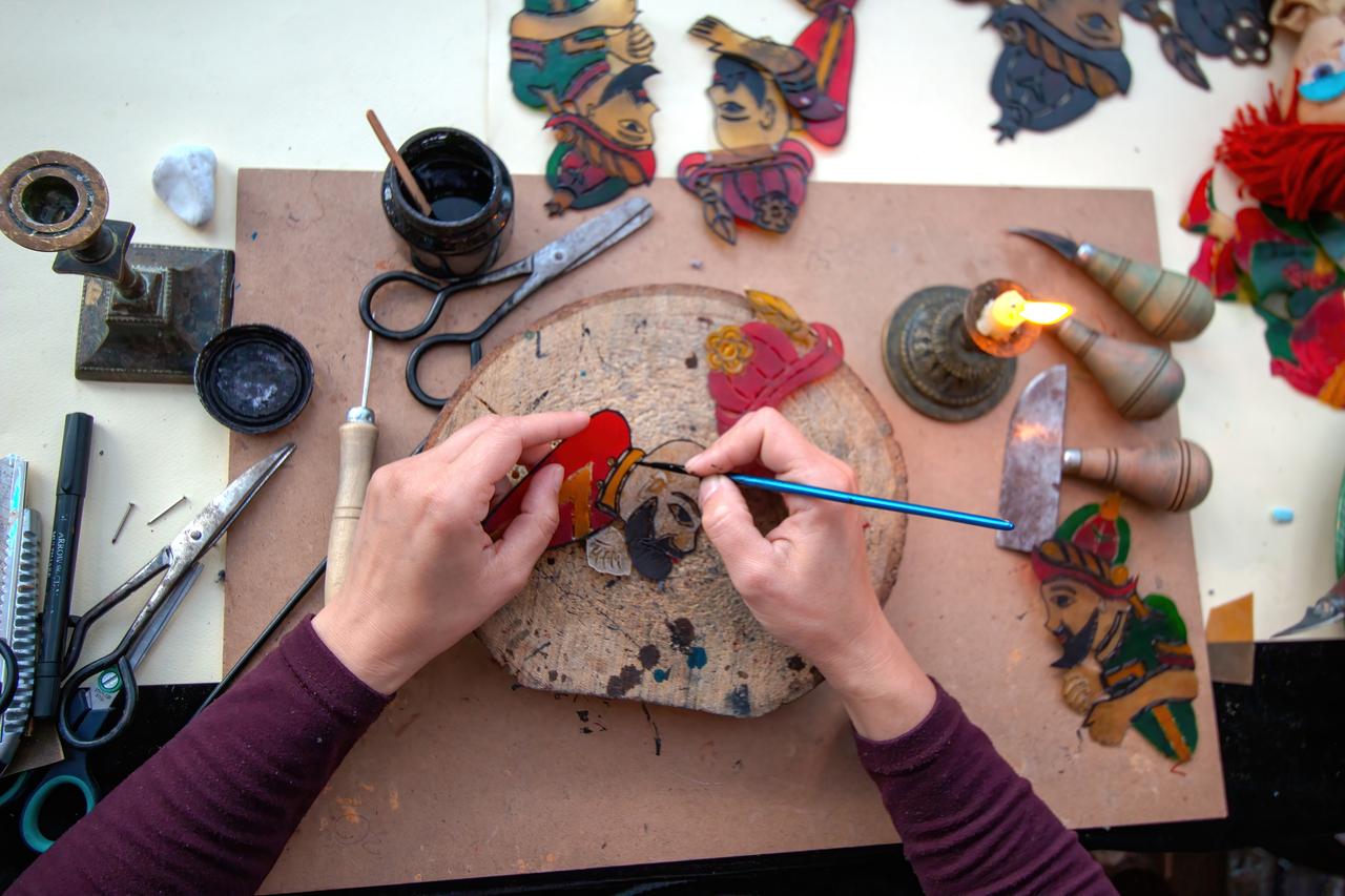 A craftsperson paints a traditional Karagoz shadow figure made from treated leather, Türkiye, accessed on March 19, 2026. (Courtesy of IBBSM)
