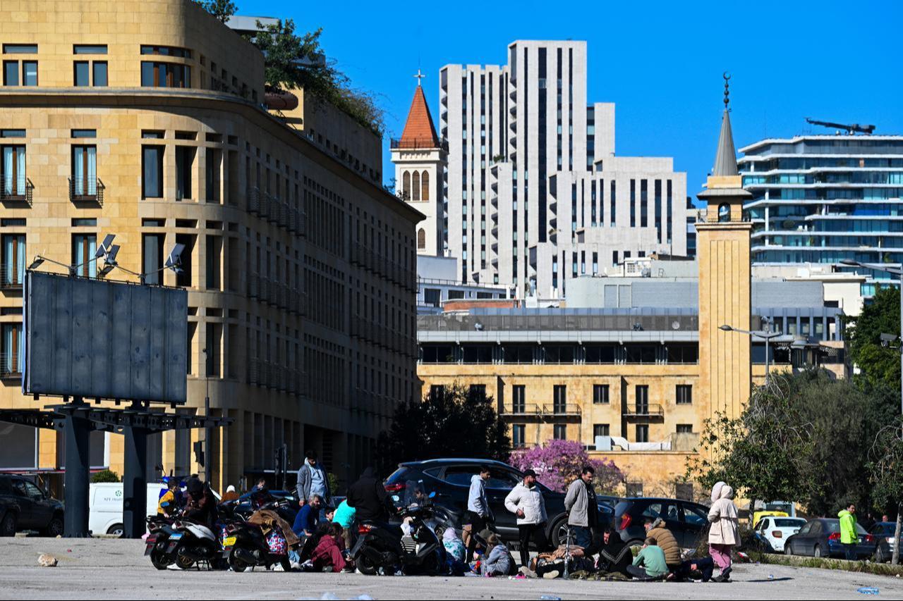 Families who fled their homes in Beirut’s southern suburbs following Israeli strikes sit in a square in the city center on March 2, 2026. (AFP Photo)