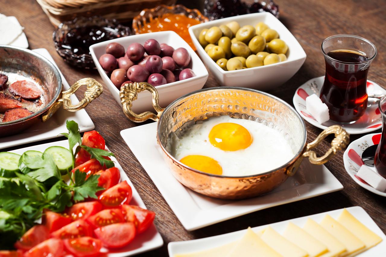 A traditional Turkish breakfast spread featuring eggs, olives, fresh vegetables, cheese and tea. (Adobe Stock Photo)