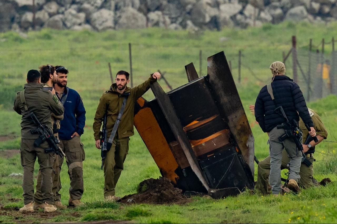 Israeli security personnel secure an area around a rocket partly buried in a field in the Israeli-annexed Golan Heights bordering Lebanon, on March 19, 2026. (AFP Photo)