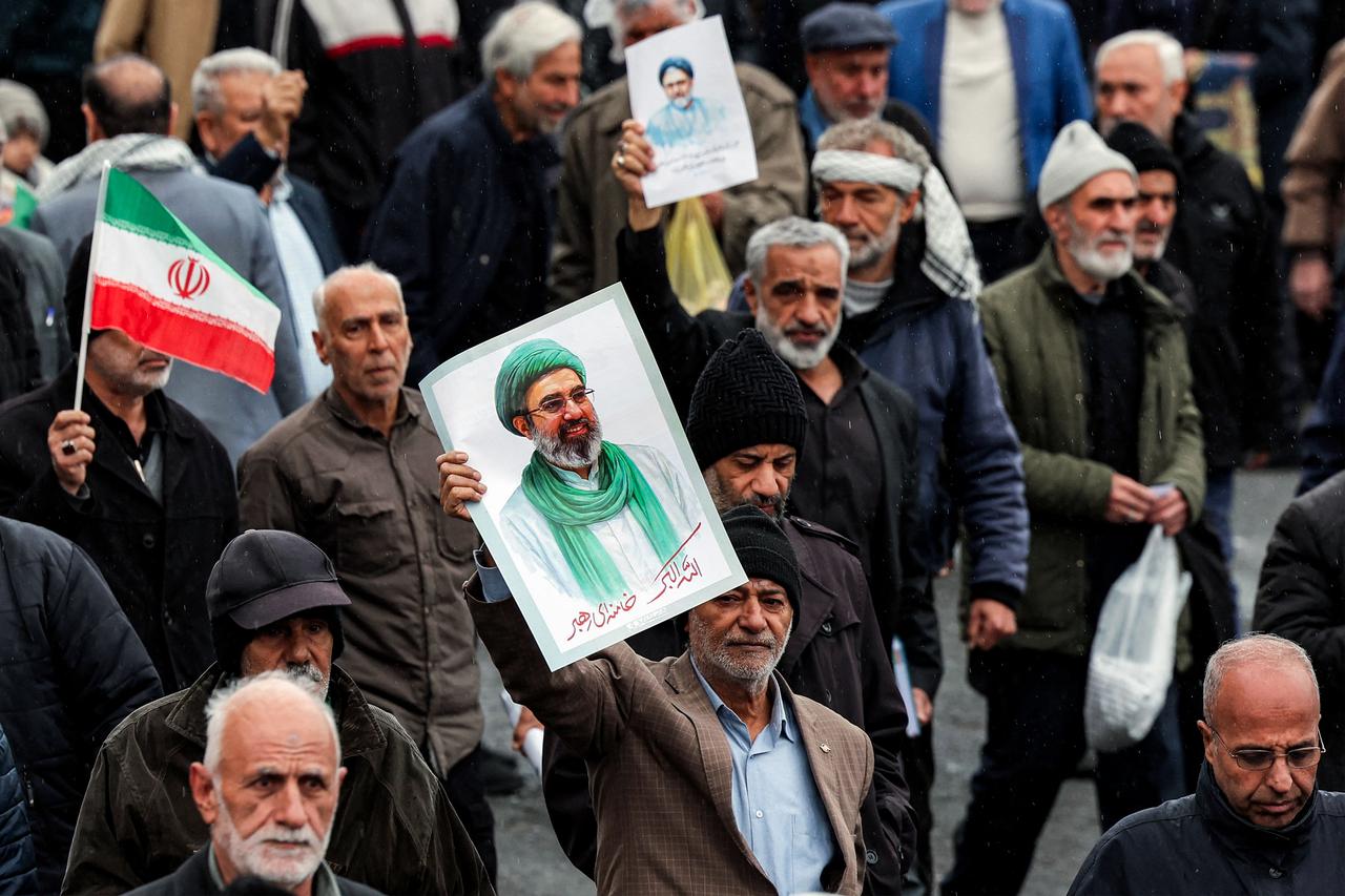 A mourner holds a picture of Iran's new supreme leader, Mojtaba Khamenei, while marching with others during a funeral ceremony in Tehran on March 20, 2026. (AFP Photo)