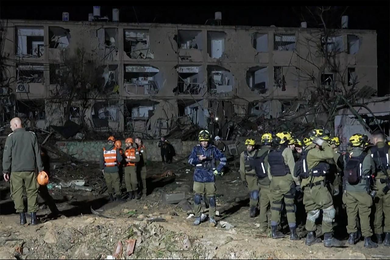 This frame grab from AFPTV footage shows first responders inspecting the site of an Iranian missile strike in Dimona on March 21, 2026. (AFP Photo)