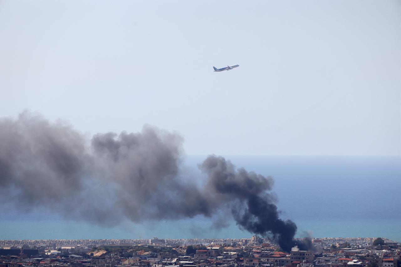 A Middle East Airlines aircraft takes off from the airport in Beirut as smoke rises from the site of an Israeli air strike that targeted an area in the southern suburbs of the Lebanese capital, March 17, 2026. (AFP Photo)