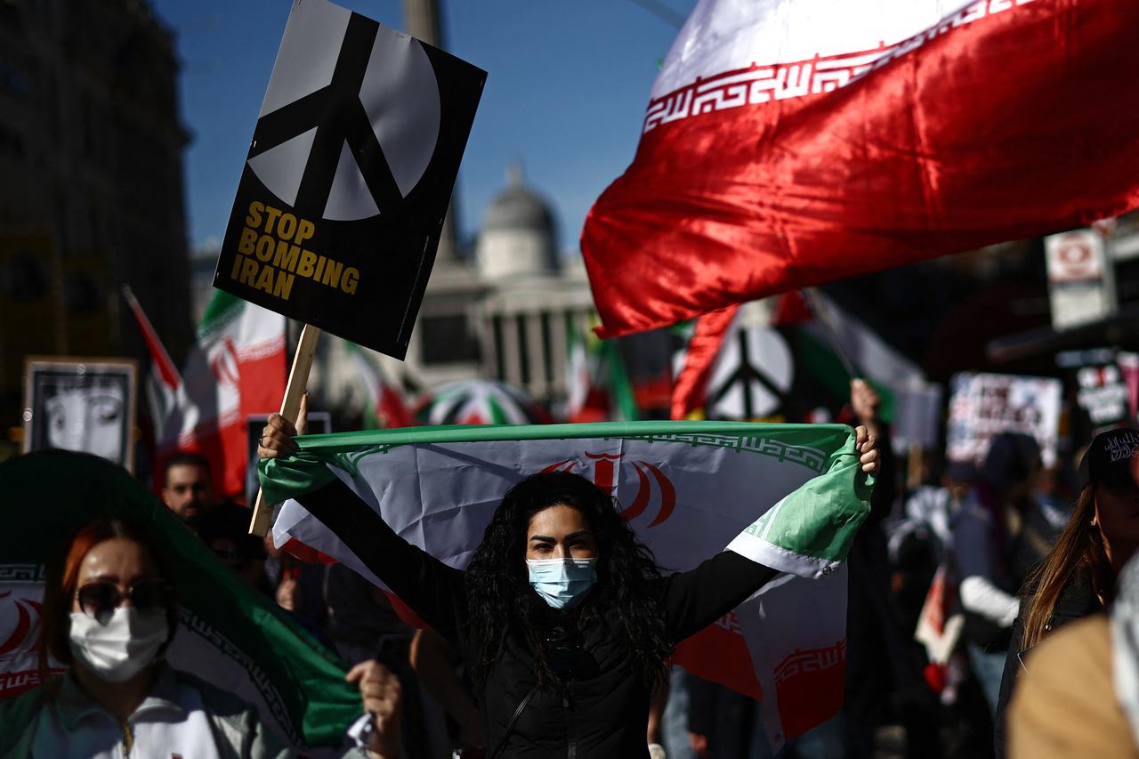 Protesters carry placards and wave Iranian flags on Whitehall during a protest march in central London on March 21, 2026, calling for the bombing of Iran to stop. (AFP Photo)