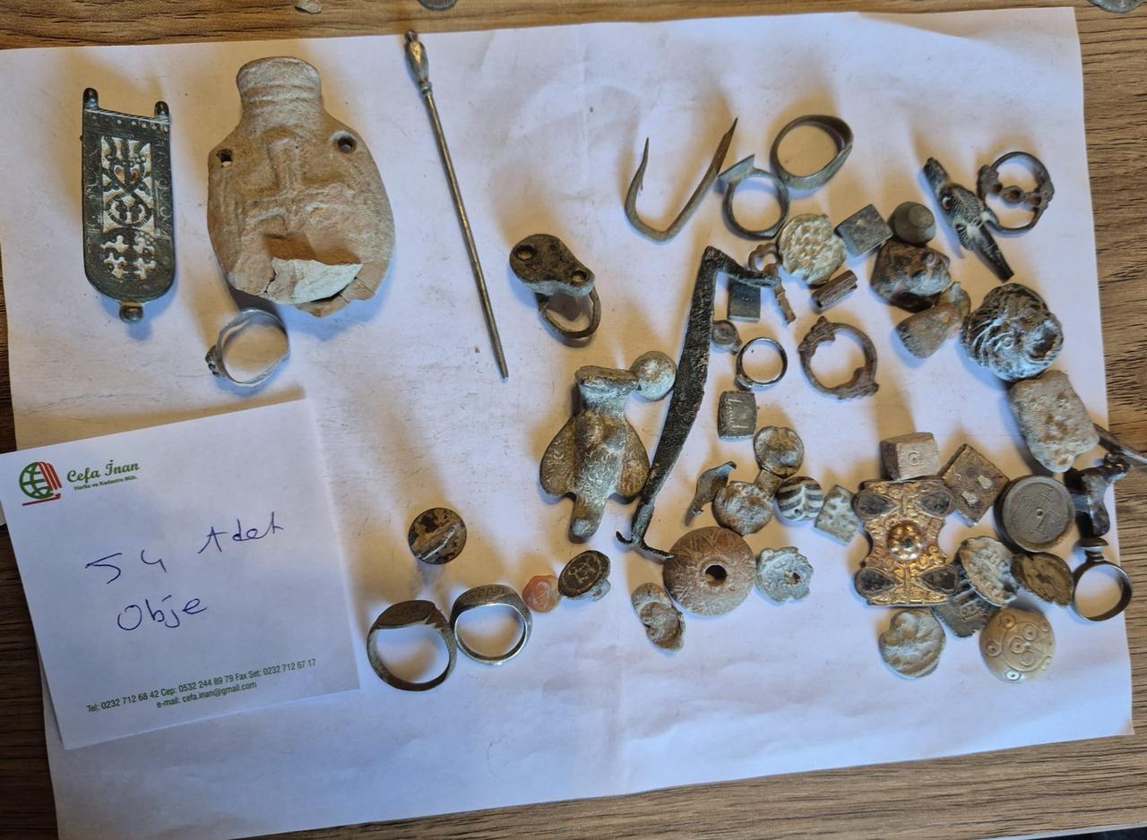 A collection of historical artifacts, including coins, rings and small figurines, seized by customs officers at Cesme Ulusoy Port is displayed following the operation, March 17, 2026. (AA Photo)