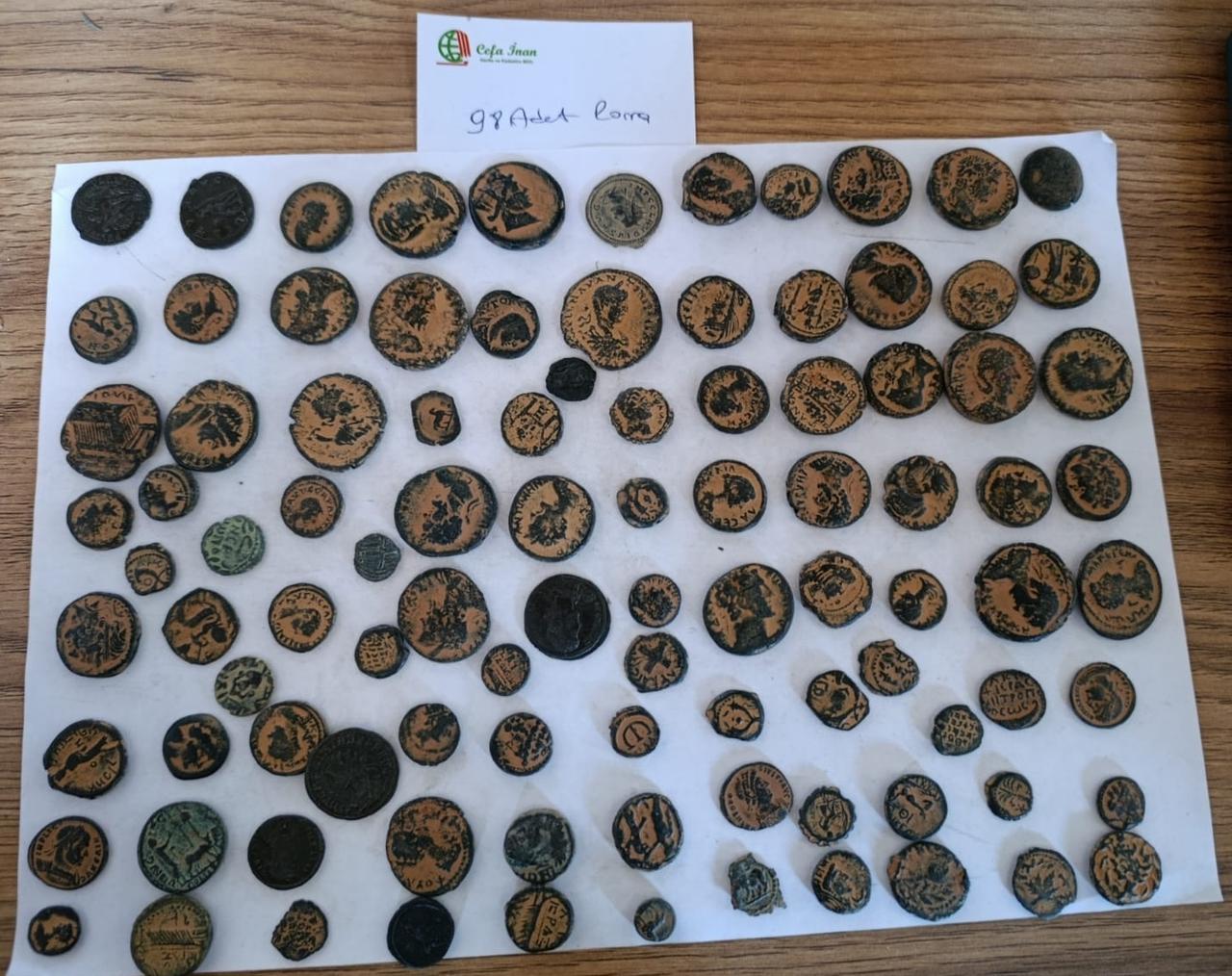 Multiple sheets of seized coins and artifacts are displayed as evidence in a smuggling case uncovered at Cesme Port, March 17, 2026. (AA Photo)