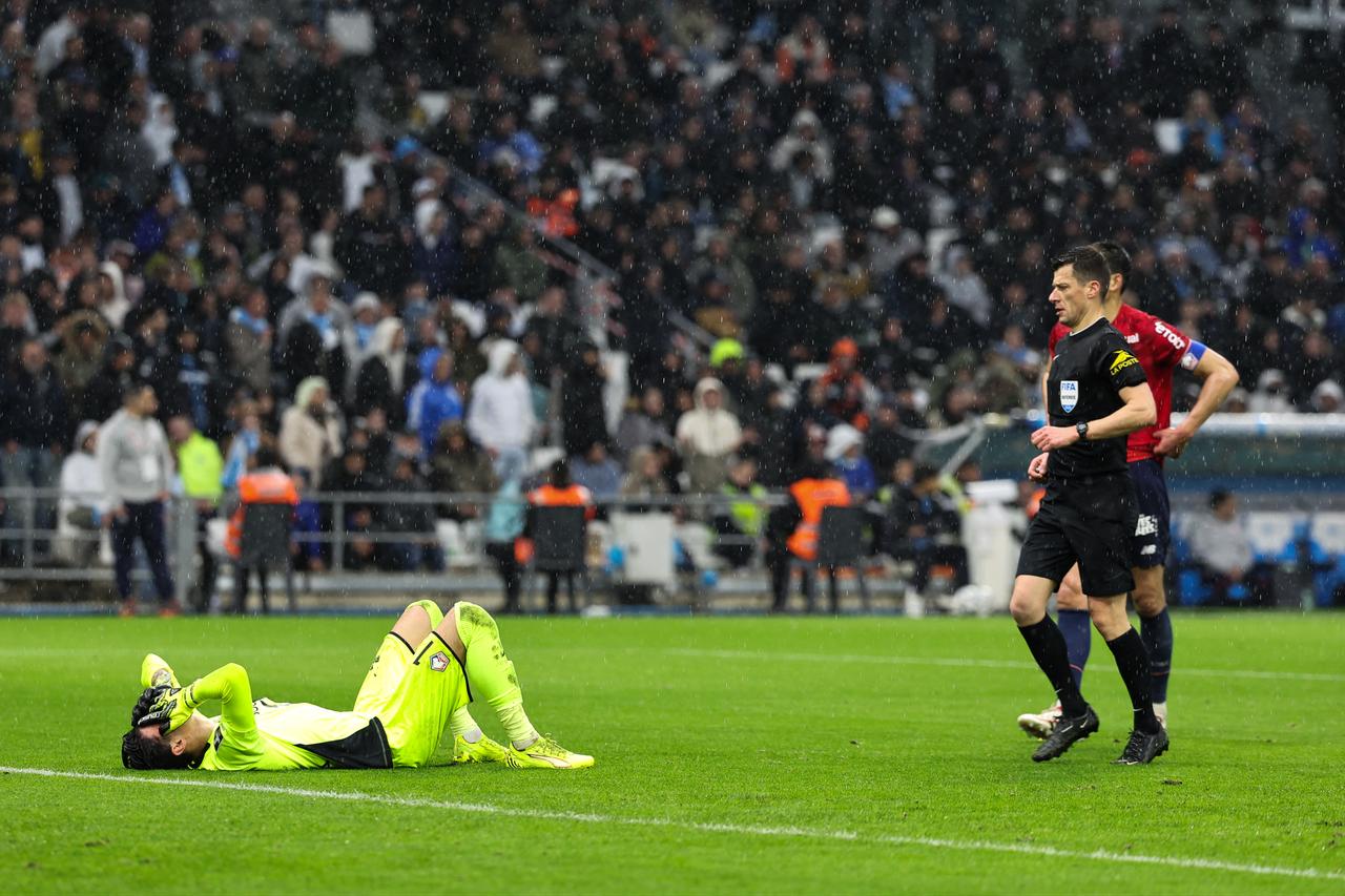 French referee Benoit Bastien (R) walks toward Lille's Turkish goalkeeper #01 Berke Ozer lying on the pitch after a contact during the French L1 football match between Olympique de Marseille (OM) and Lille OSC at the Stade Velodrome in Marseille, southern France, March 22, 2026. (AFP Photo)