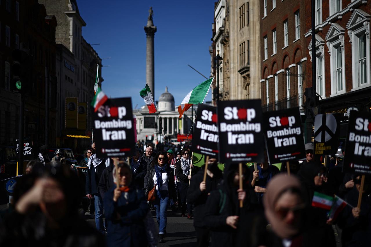 Protesters carry placards on Whitehall during of a protest march in central London on March 21, 2026, calling for the bombing of Iran to stop. (AFP Photo)