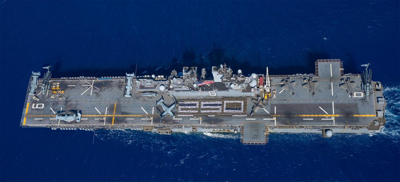 Sailors assigned to the forward-deployed amphibious assault ship USS America (LHA 6) and U.S. Marines stand in formation in the Coral Sea, Aug. 2. 2025. (Photo via U.S. Navy)