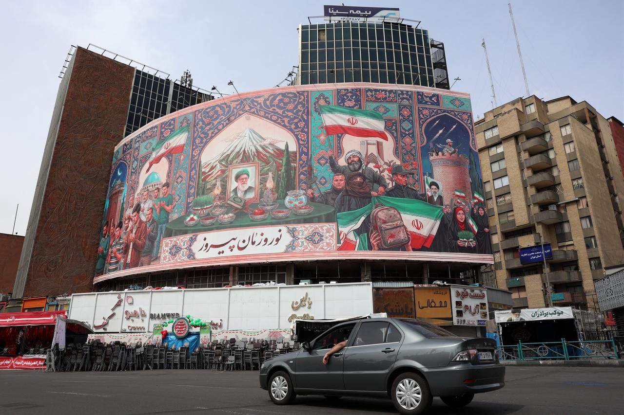 A car drives past a giant billboard with a portrait of Iran's slain supreme leader Ali Khamenei (C) at the Valiasr Square in Tehran, Iran on March 22, 2026. (AFP Photo)