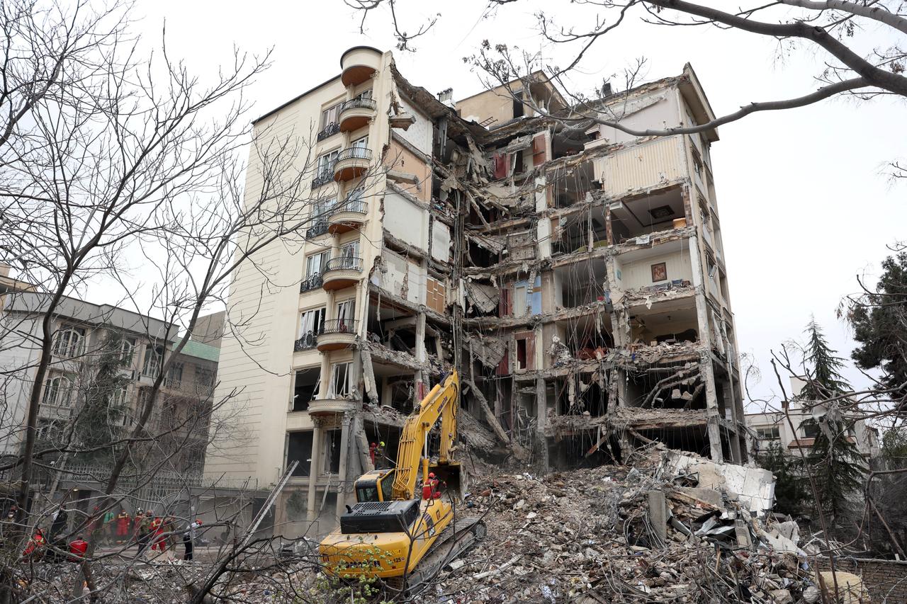 Iranian firefighters with the help of an excavator clear rubble from a destroyed residential building in northern Tehran, Iran on March 23, 2026. (AFP Photo)
