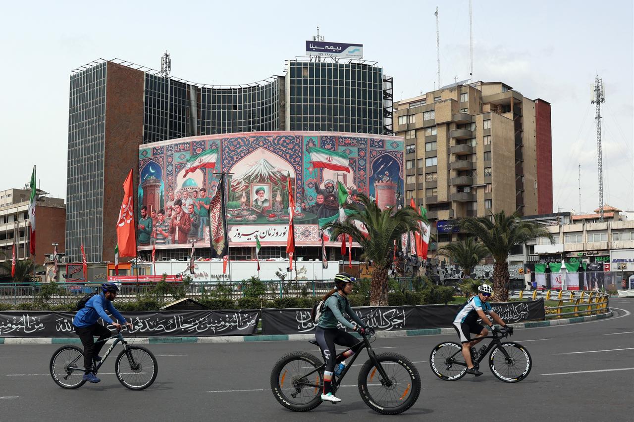 Cyclists ride past a giant billboard with a portrait of Iran's slain supreme leader Ayatollah Ali Khamenei (C) at the Valiasr Square in Tehran, Iran on March 22, 2026. (AFP Photo)
