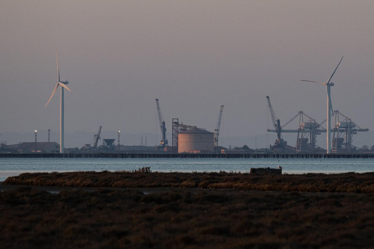 This photograph shows cranes, a storage tank of an oil refinery and wind turbines at the deep-water commercial and industrial port of Fos-sur-Mer, near Marseille, southern France, on March 20, 2026. (AFP Photo)