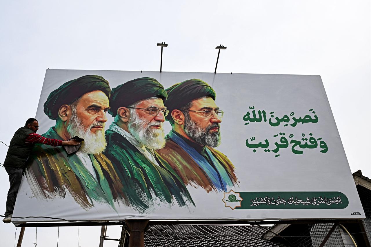 A man cleans a billboard featuring Iran's late supreme leaders Ruhollah Khomeini (L) and Ali Khamenei (C) next to newly elected supreme leader Mojtaba Khamenei, on the outskirts of Srinagar, March 23, 2026. (AFP Photo)