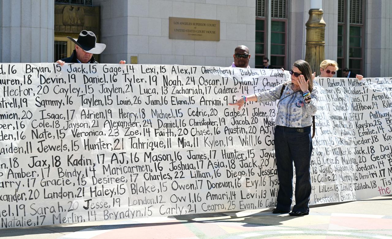 Mary Rodee, whose 15-year-old son died by suicide, points to a banner listing victims’ names outside the Los Angeles Superior Court, United States, March 25, 2026. (AFP Photo)