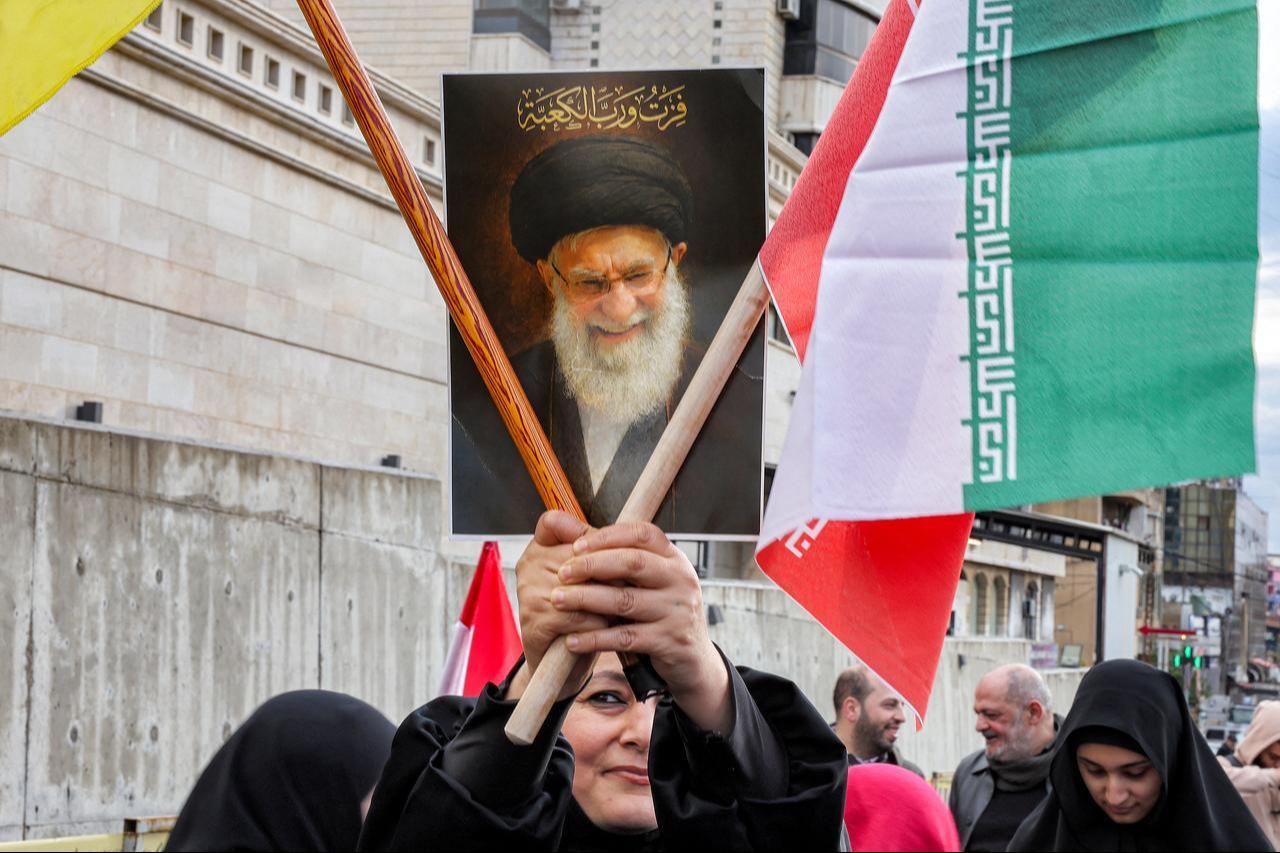 A woman holds a sign depicting Iran's late supreme leader Ali Khamenei during a rally organised by Lebanese political parties supporting the Hezbollah movement outside the Iranian embassy in Beirut on March 26, 2026. (AFP Photo)