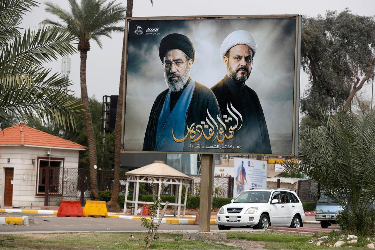 A car drives past a billboard bearing images of Iranian Supreme Leader Mojtaba Khamenei and Akram al-Kaabi, Secretary-General of the Kataib al-Nujaa, in Baghdad, Iraq on March 21, 2026. (AFP Photo)