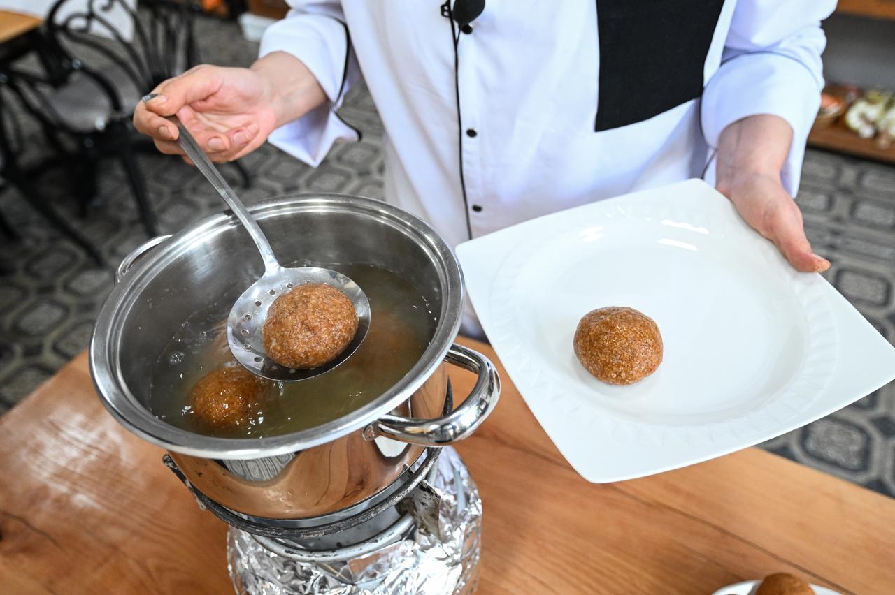 A chef removes boiled Adana icli kofte from a pot of simmering water before plating in Adana, Türkiye, March 3, 2026. (AA Photo)