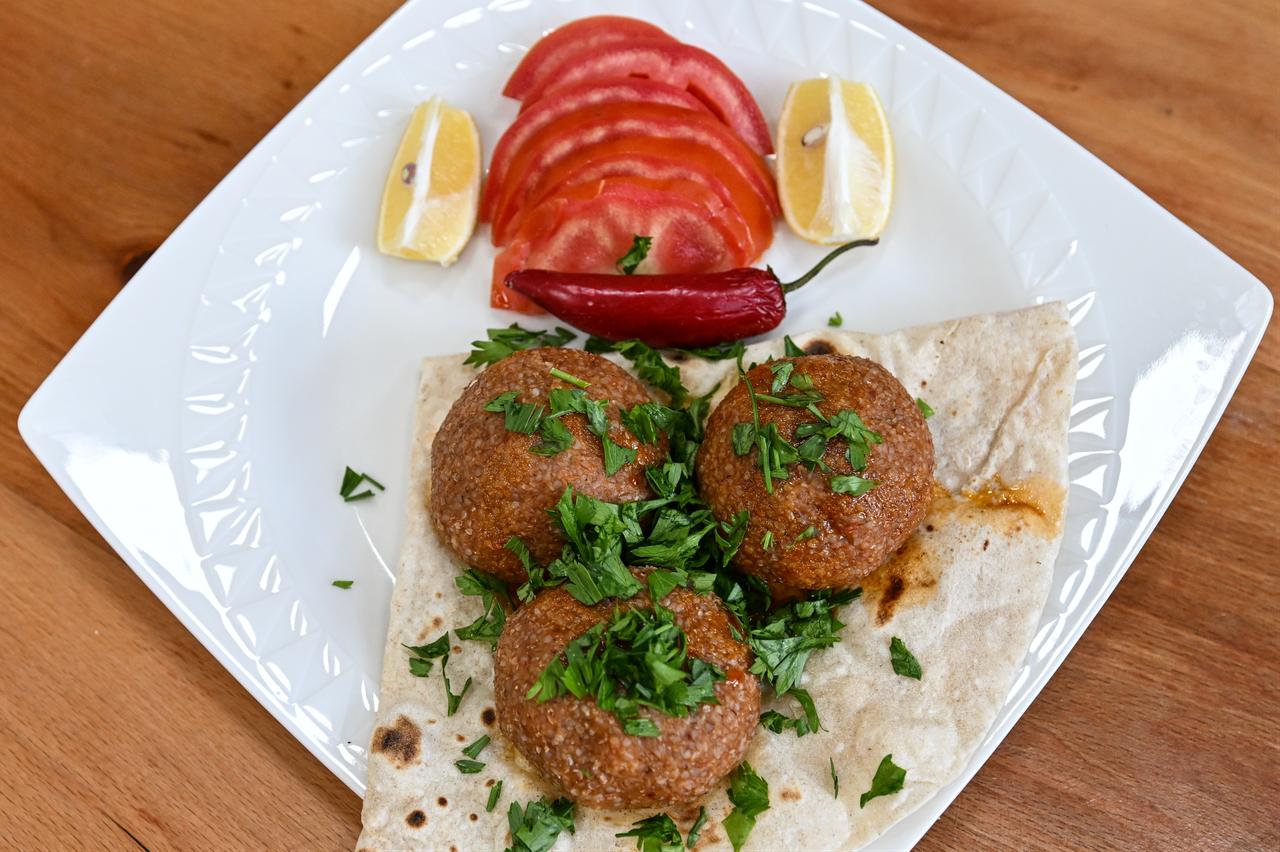 Boiled Adana icli kofte is served on flatbread with parsley, tomato slices, red pepper and lemon wedges in Adana, Türkiye, March 3, 2026. (AA Photo)