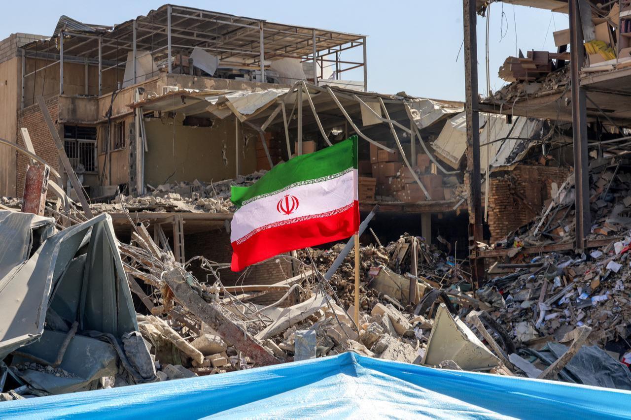 An Iranian flag is placed amids rubble and debris next to a destroyed residential building near Ferdowsi square in Tehran on March 3, 2026. (AFP Photo)