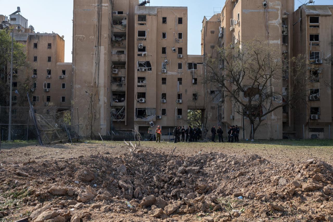 Members of the Israeli security forces stand next to a crater at the scene of an Iranian missile strike in Beersheva on March 2, 2026. (AFP Photo)